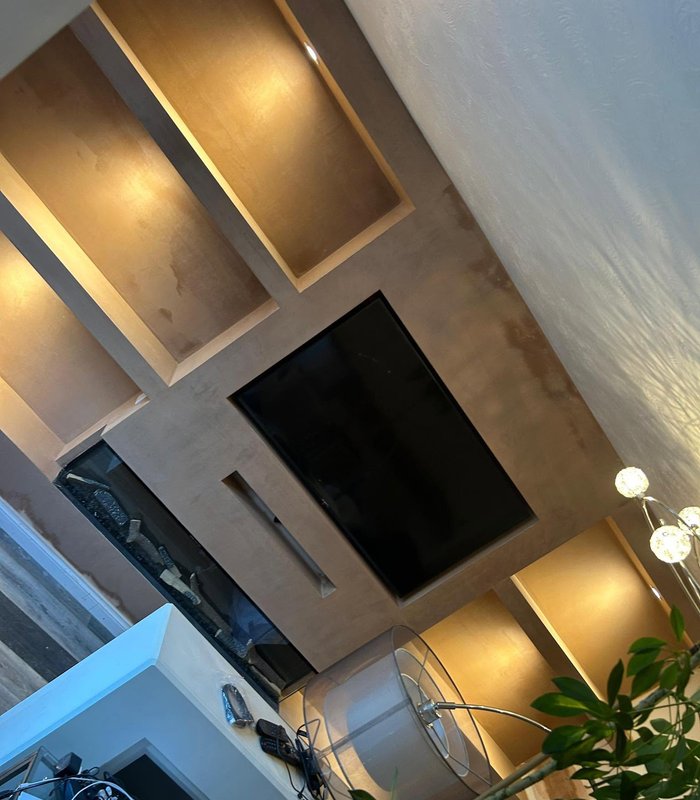 Plastered media wall with recessed illuminated shelving