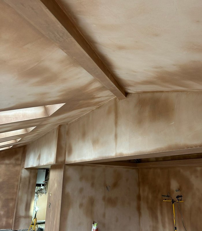 Plastering work in progress across an interior ceiling and beam